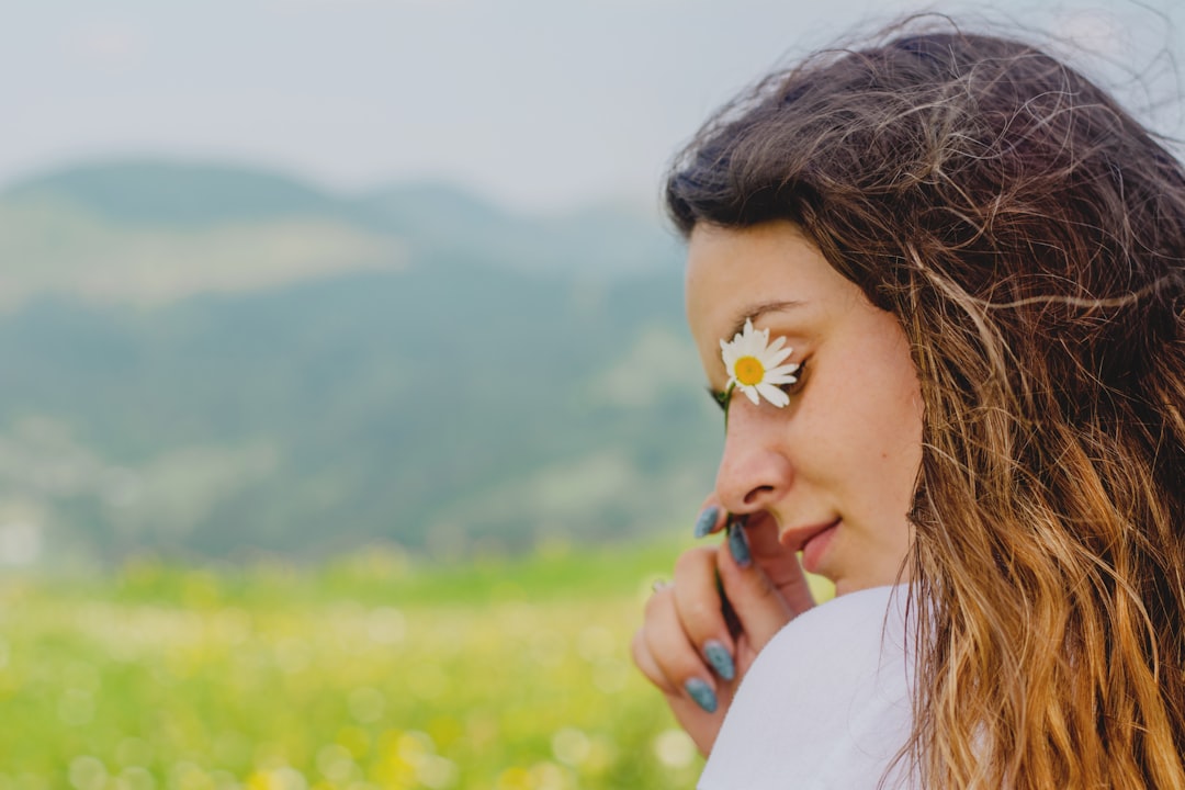 woman in white shirt with yellow flower on ear
