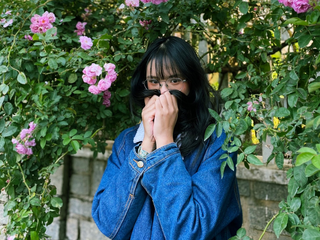 woman in blue denim jacket covering her face with her hands