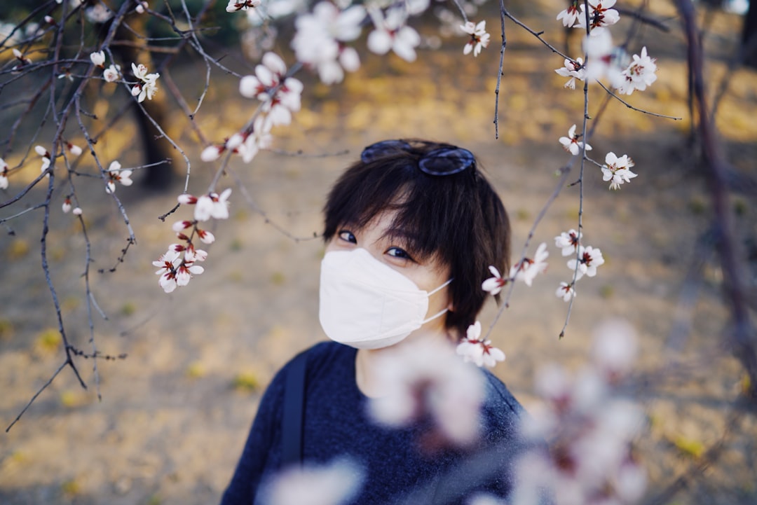 woman in blue sweater standing under brown leaf tree during daytime