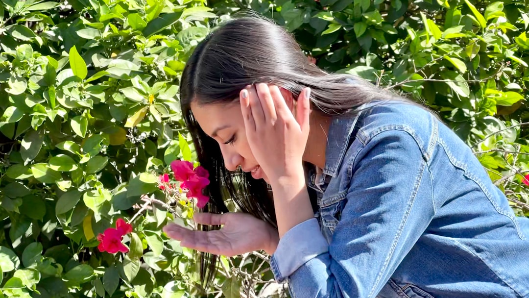 woman in blue denim jacket covering face with her hand