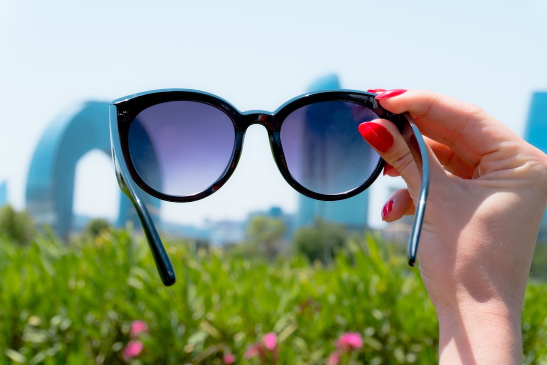 Woman holding sunglasses with city buildings behind