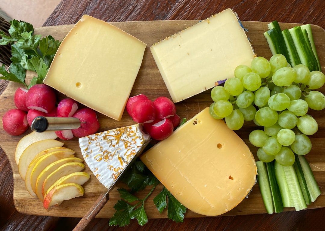 a wooden cutting board topped with cheese and fruit