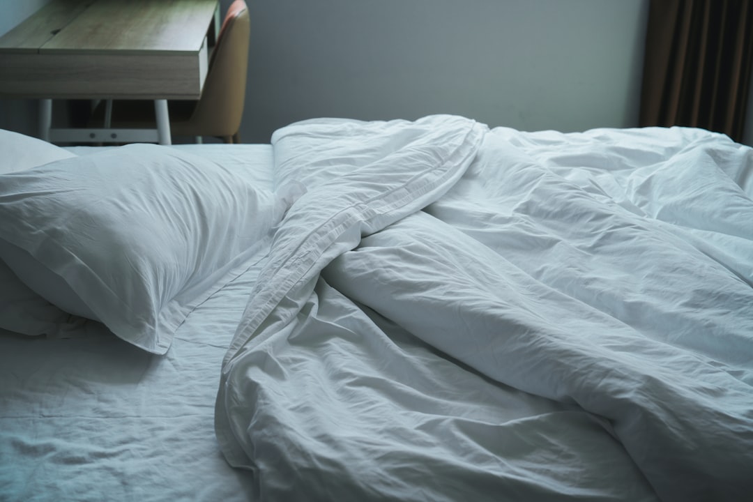 An unmade bed with white sheets and a night stand