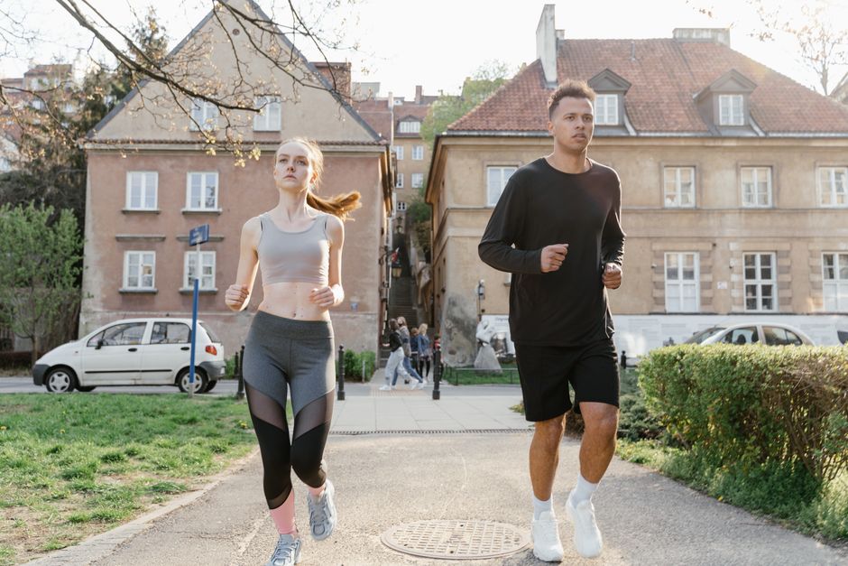 Two young adults jogging on a city path, showcasing an active lifestyle in an urban environment.