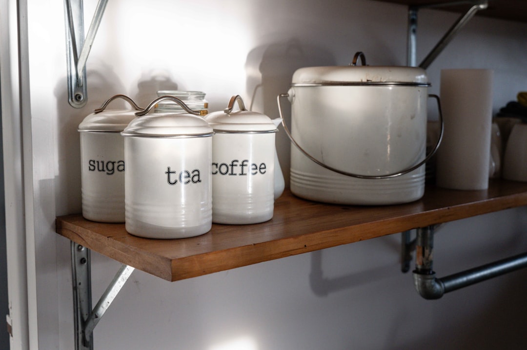 White canisters labeled sugar, tea, and coffee on shelf.