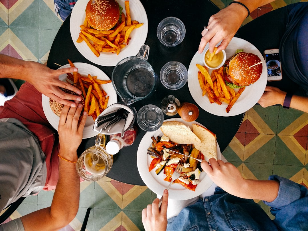 People eating burgers, fries, and roasted vegetables at a round table
