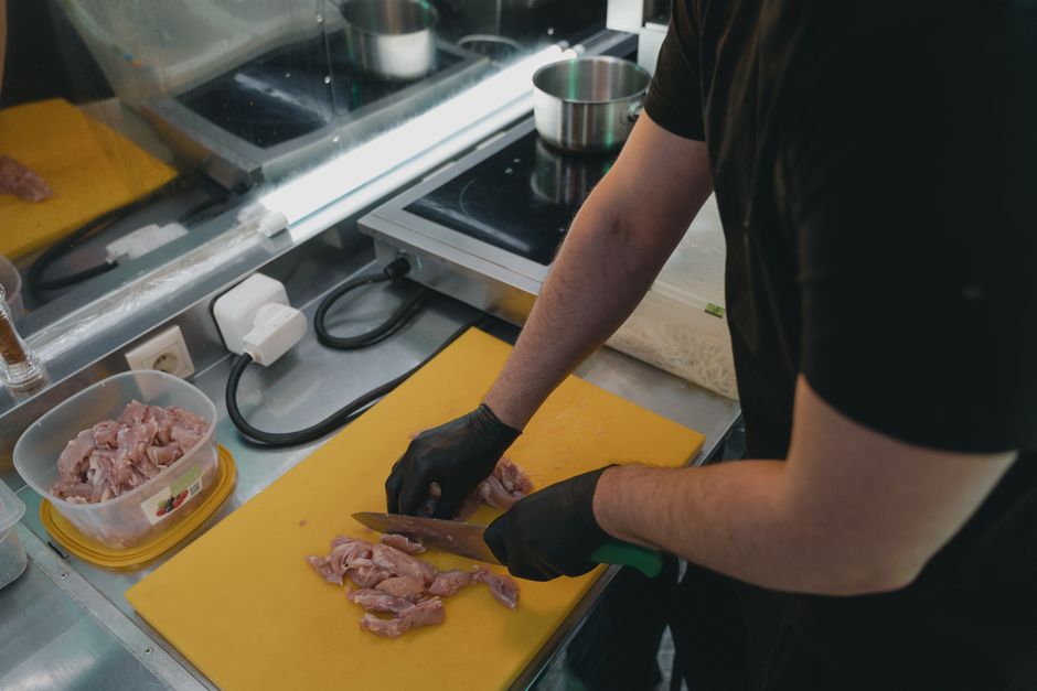Man slicing raw meat on a yellow cutting board in a modern kitchen setting.