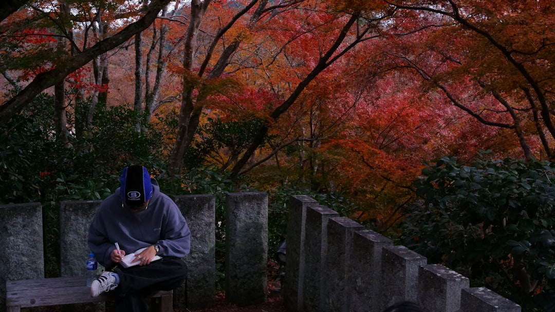 Person sitting outdoors amidst autumn foliage